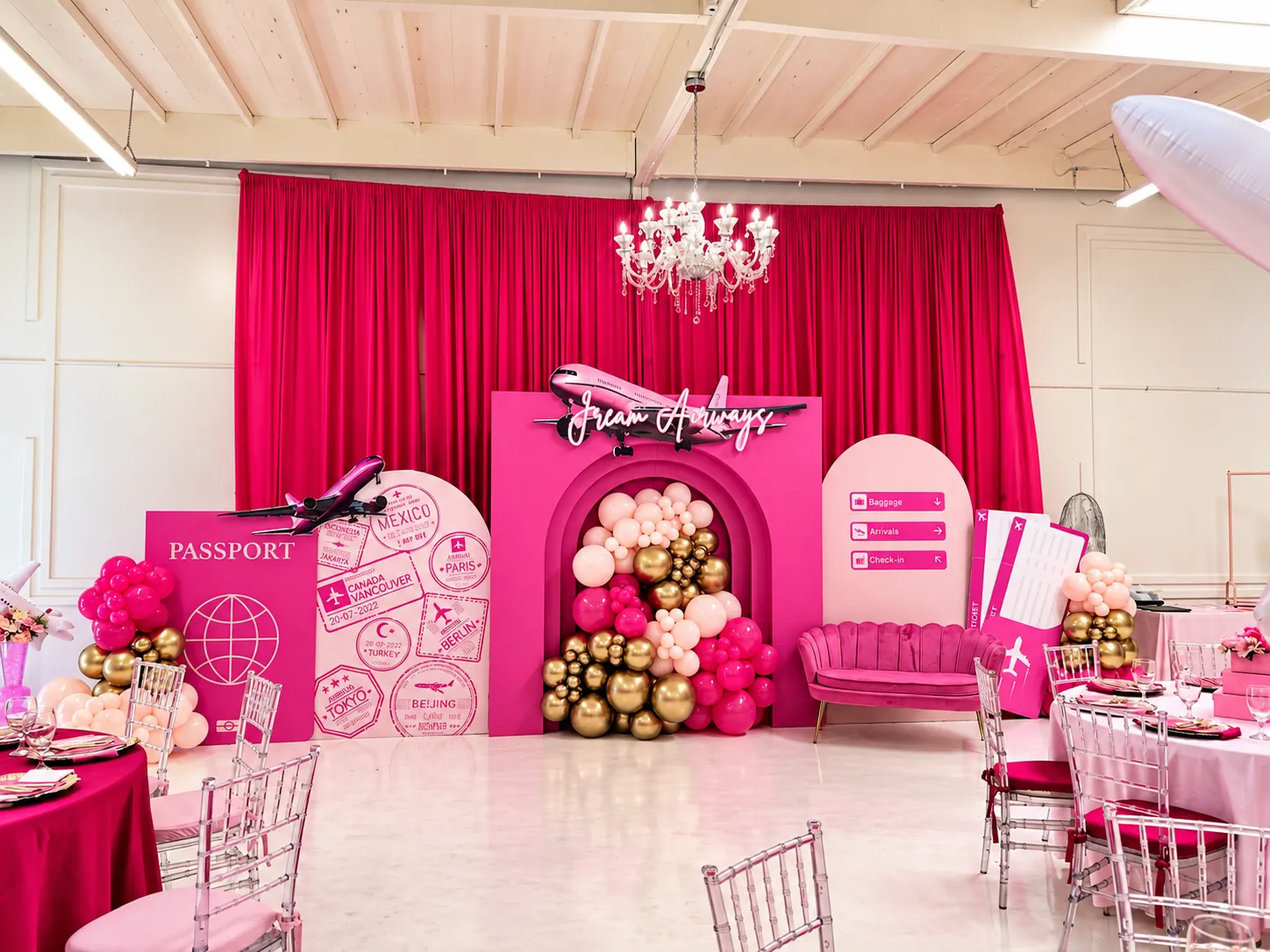 Pink 'Dream Arrivals' travel-themed backdrop with passport, balloons and airplane